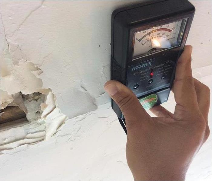 moisture meter against water damaged ceiling