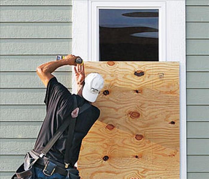men boarding up a window to a house